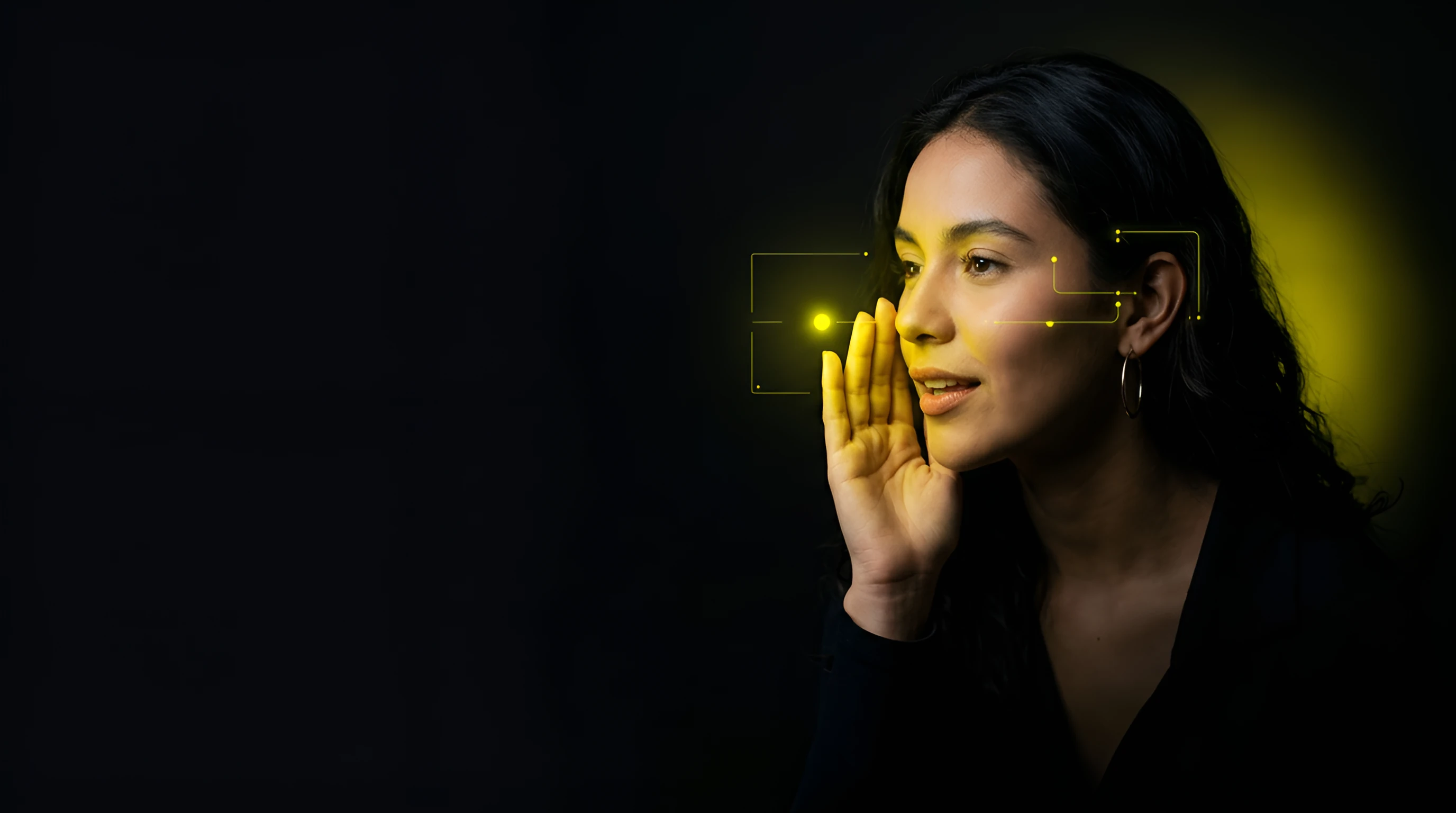 Woman with long dark hair cupping a hand to her mouth as if sharing a secret, glowing yellow tracking brackets beside her face against a dark backdrop