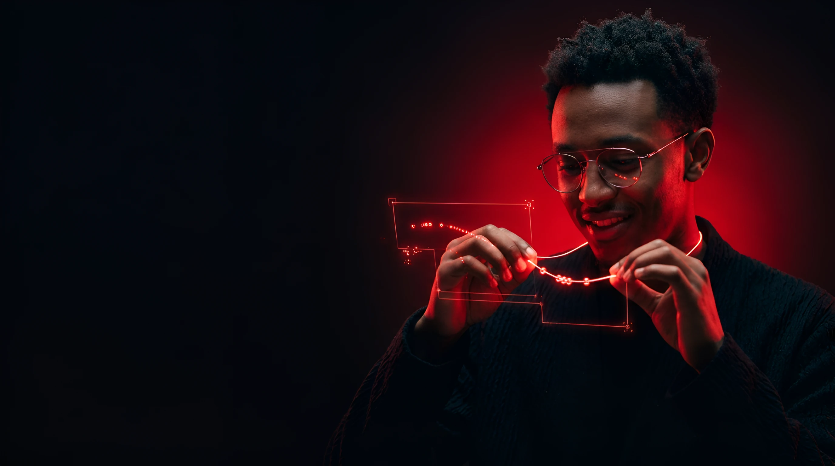 Young Ethiopian man in wire glasses stringing tiny red beads onto a glowing YouTube-red thread like a necklace of tracking nodes